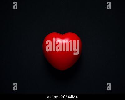 Red heart on black background. Single red ball foam with heart shape. Love, care, and Valentine Day Concept. Stock Photo