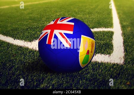 Turks And Caicos Islands flag on ball at corner kick position, soccer field background. National football theme on green grass. Stock Photo