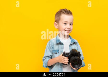 Happy child hold professional photo camera, smiles and looks at the camera. Photographer's Day concept Stock Photo