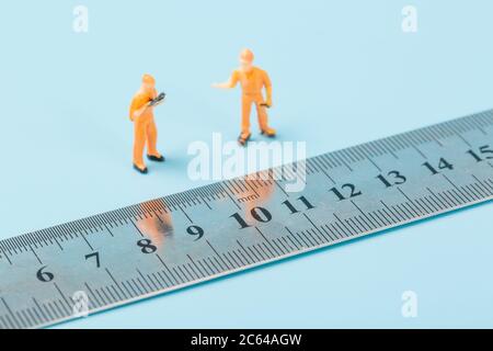 Steel ruler and yellow villain on blue background Stock Photo