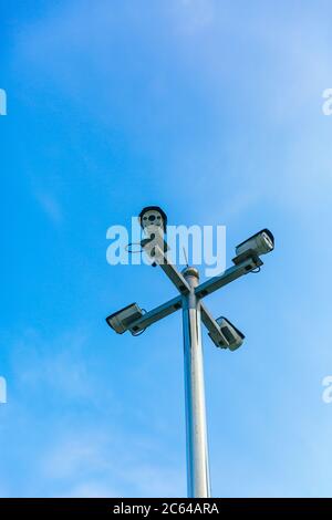 Surveillance camera mounted on a pillar under a blue sky Stock Photo