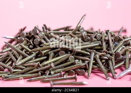 Messy stacked metal nails on pink background Stock Photo