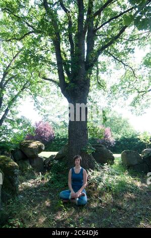 Meditating woman in the forest Stock Photo