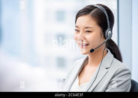 Smiling beautiful Asian female customer service operator working in call center office Stock Photo