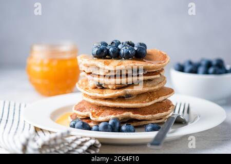 Whole wheat pancakes with blueberries and honey on a plate. Tasty breakfast food, stack of homemade pancakes Stock Photo