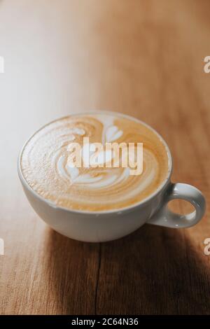 The art of drawing on milk foam when making latte and cappuccino in a white cup on a bar table Stock Photo