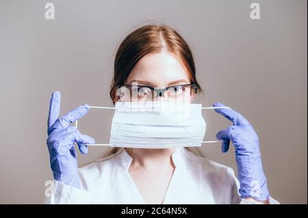 Female doctor in a white coat showing face mask or medical mask to protection from coronavirus Stock Photo