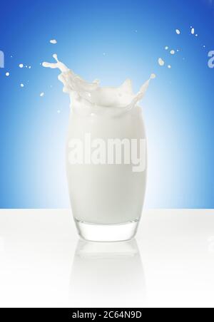 milk splashing in a glass isolated on blue background Stock Photo