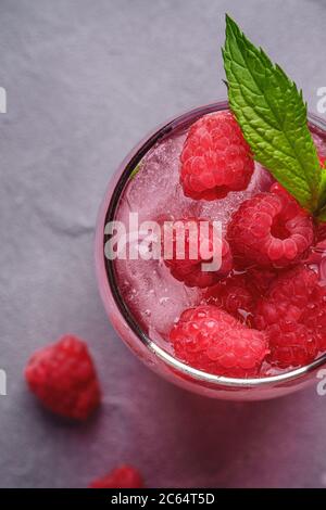 Fresh ice cold berry juice drink with mint, summer raspberry lemonade in glass on stone concrete background, top view macro Stock Photo