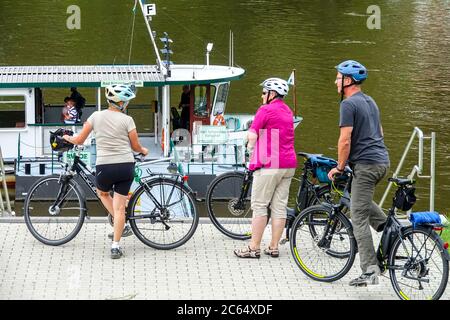 Elbe river ferry boat and seniors on bicycles Bad Schandau Germany people on the cycle path, people waiting to embark, boarding Stock Photo