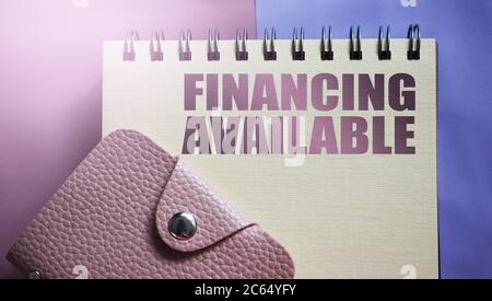 Financing available text in copybook, pink leather wallet. Business concept. Stock Photo