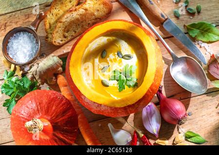 Squash soup served in a pumpkin on rustic wooden table Stock Photo