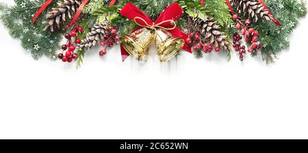 Decoration from snowy pine branches, cones, holly and Christmas bells isolated on white background Stock Photo