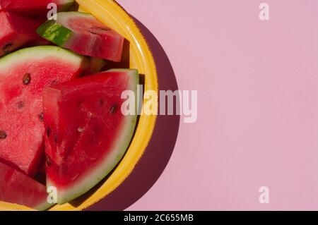 Fresh sliced watermelon in yellow plate on pink background. Stock Photo