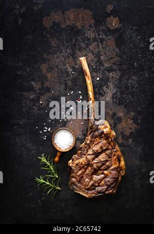 Grilled tomahawk beef steak with spices on dark rustic background Stock Photo