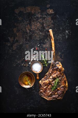 Grilled tomahawk beef steak with spices on dark rustic background Stock Photo