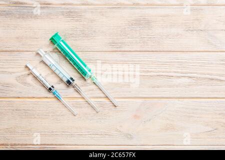 Top view of syringes of different sizes on wooden background. Medical equipment for injection concept with copy space. Stock Photo