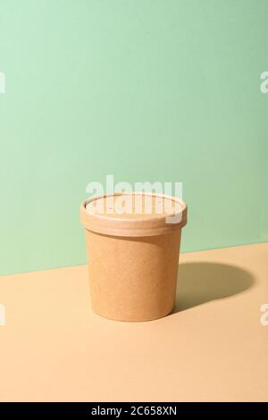 Craft paper soup cup with shadow on green and brown paper.Ecological individual package. Zero Waste. Stock Photo