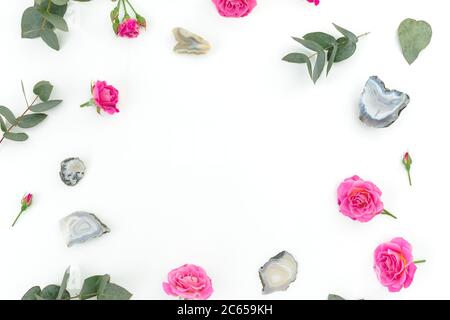 Floral frame with eucalyptus, roses flowers and Agate stones on white background. Flat lay Stock Photo
