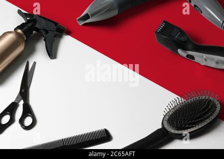 Indonesia flag with hair cutting tools. Combs, scissors and hairdressing tools in a beauty salon desktop on a national wooden background. Stock Photo