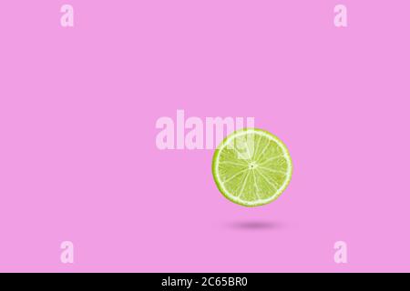 Falling lime isolated on white background. Green lime slic on vibrant pink color background. Minimal summer concept. lime levitation Stock Photo