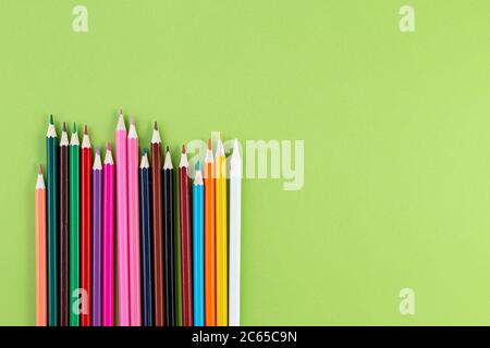 Colored pencils on a green background. Colorful wooden pencils. Flat lay, Top view with copy space Stock Photo