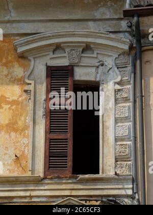 View of a framed and broken window with a missing shutter Stock Photo