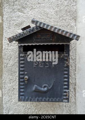 Old metallic post box located on a stone wall captured in Italy Stock Photo