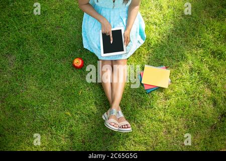 Top view of unrecognizable African American girl using tablet computer with blank screen on green lawn Stock Photo