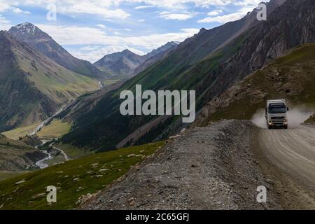 Container trucks driving on the well maintained dirt road to the Kumtor Gold Mine.Kyrgyzstan Stock Photo
