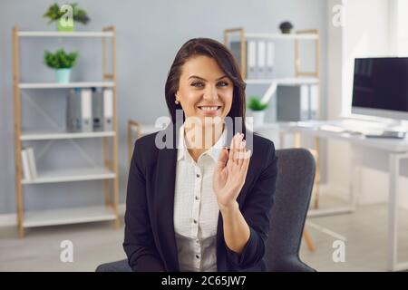 Businesswoman in a black suit looking at the camera talking to a partner while sitting in the office. Stock Photo