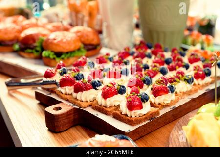 Desserts and burgers on table, hotel dinner board, toned Stock Photo