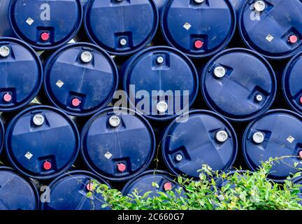 Closeup stack of chemical barrels. Blue oil drum. Plastic oil tank. Toxic waste warehouse. Hazard chemical barrel with warning label. Industrial waste Stock Photo