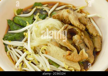 boiled thin rice noodles chicken leg and feet with bean sprout in herb brown soup on bowl Stock Photo