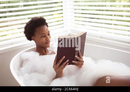 Woman reading book in a bathtub Stock Photo