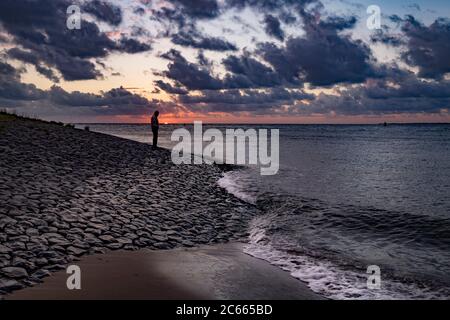 A man stands on the coast of Den Helder at sunset, Holland, Netherlands Stock Photo