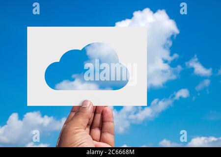 Internet Cloud Concept. Man holds a sheet of paper with cloud shaped cut-out against the blue sky. Stock Photo