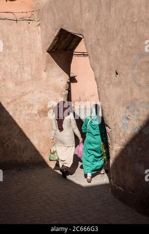 Two women in a caftan walking through an oriental archway, Marrakech, Morocco Stock Photo