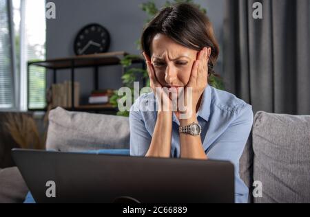 Mature woman feeling sad while looking at computer screen Stock Photo