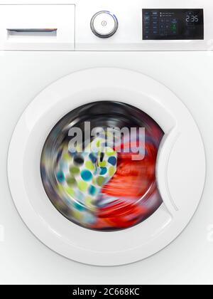 Front close up of a modern electronic washing machine with rotating colorful laundry Stock Photo
