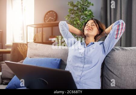Charming lady relaxing on couch during remote work on laptop Stock Photo