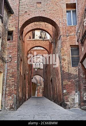 Siena, Tuscany, Italy: ancient alley with arches in the old town of the picturesque medieval city Stock Photo