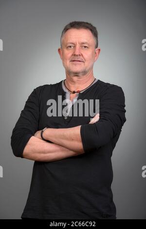 Photo of a confident man with crossed arms standing in front of a ...