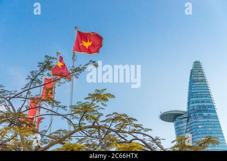 Bitexco tower under the blue sky next to a row of Vietnamese flags and the Vietnam Communist Party flags in Ho Chi Minh city, Vietnam. Concept of poli Stock Photo