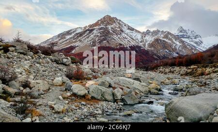 River surrounded by autumnal landscape, mountain in the background, Argentina Stock Photo