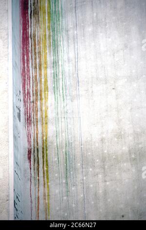 The brightly colored streaks and blobs of bleeding paint on a concrete facade, Stock Photo