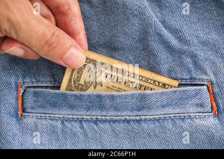 Person taking out a one dollar bill from jeans pocket. Close up. Stock Photo