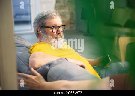 Cozy talking. Couple of seniors spending time together being quarantined - mature and retired man and woman discussing, talking, drinking tea. Eyes tired of gadget's. Cozy domestic evening. Lifestyle. Stock Photo