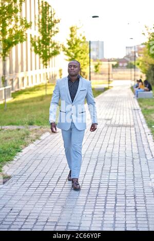 Stylish businessman walking down the street. He wears business clothes and is outdoors. Stock Photo