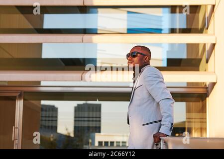 African-American man in a fancy suit enjoying the sunset outside the office. Stock Photo